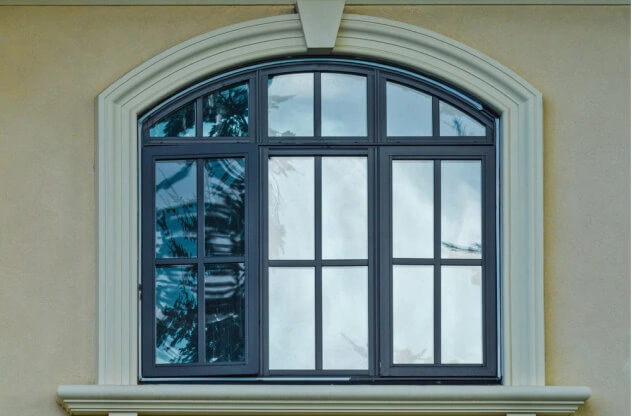 Custom black arched window on a house with a beige stucco exterior